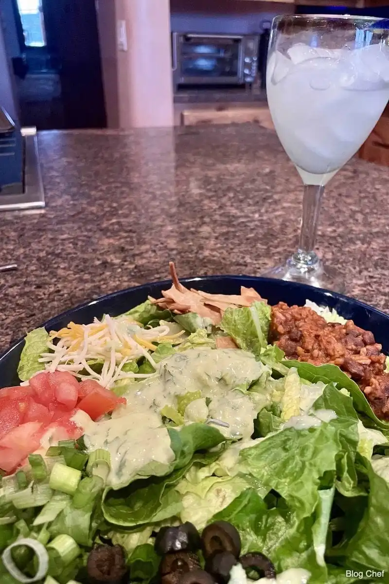 View of chopped taco salad on counter with margarita.